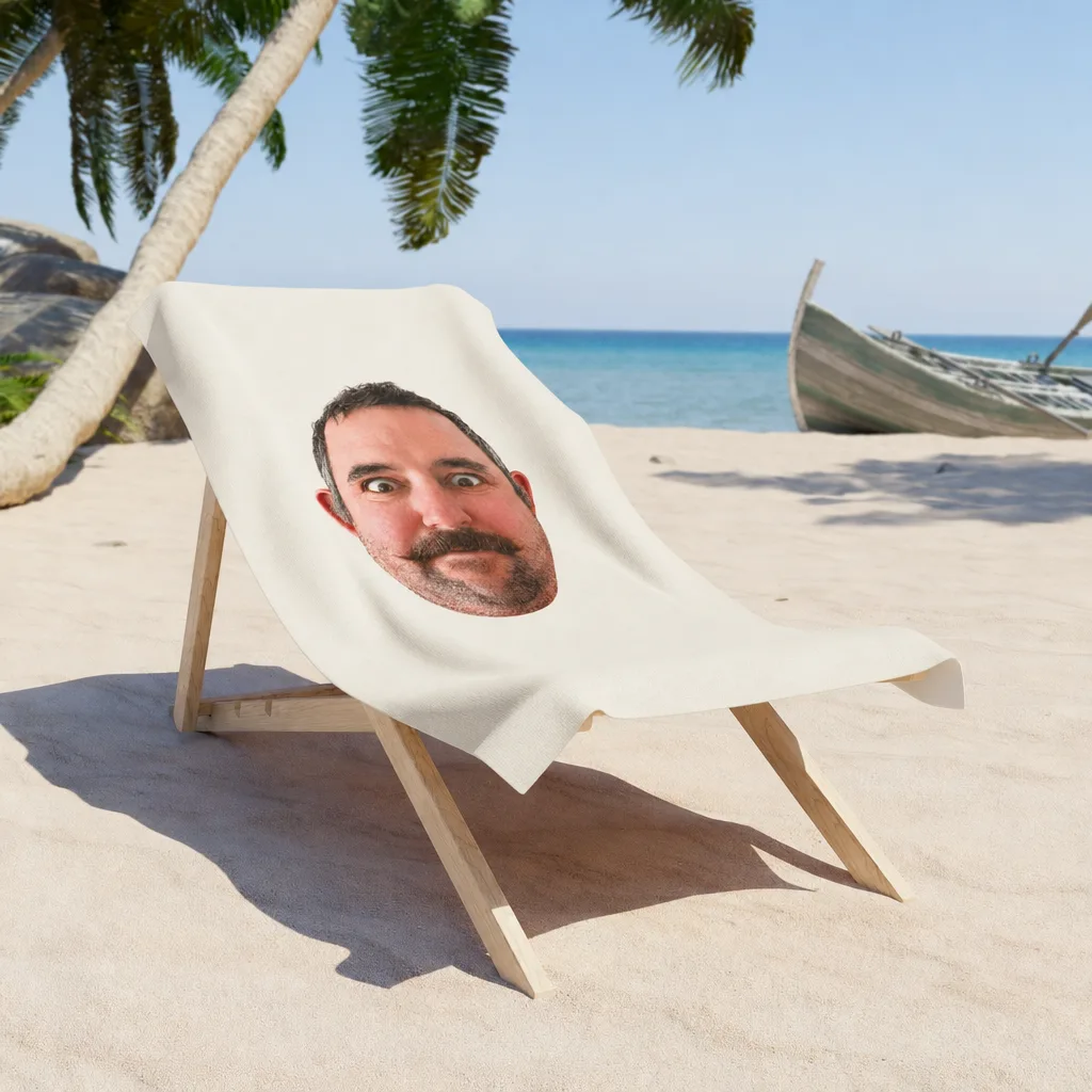 The beach towel over a chair on the sand, our picture printed in the middle of it.